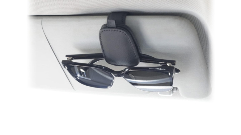 A sunglass holder by Yuoyar and a pair of sunglasses resting on the sun visor.