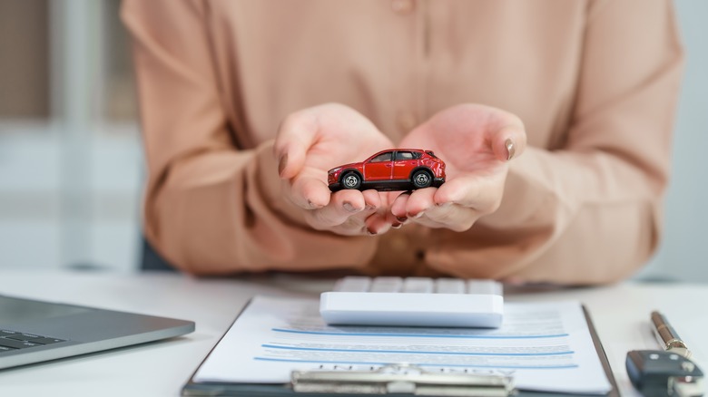 Person holding toy car and going over car expenses