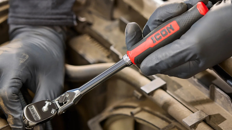 A technician with gloved hands using Harbor Freight's ICON G2 ratchet to remove bolts in an engine bay.