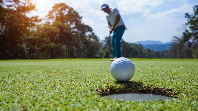 Golfer putts ball into hole