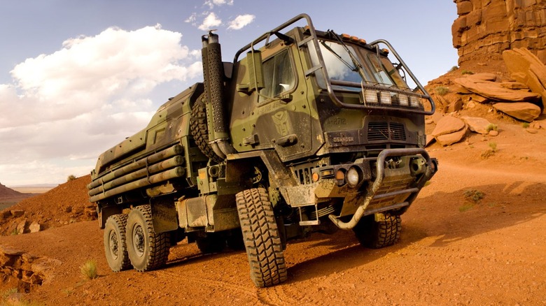 An Oshkosh Defense FMTV pictured in full camouflage livery in the desert