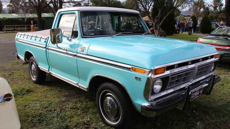 1977 Ford F-100 Ranger XLT pickup in a bright blue color parked on the grass at a car show