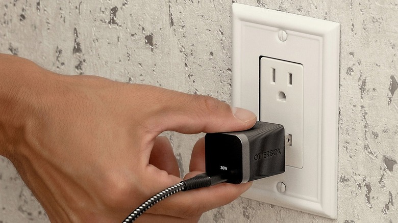 Hand plugging the Otterbox Premium Pro Fast Charge into an outlet.