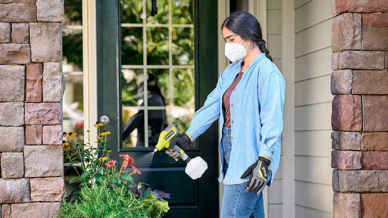 Woman using a Ryobi USB Lithium sprayer in garden.