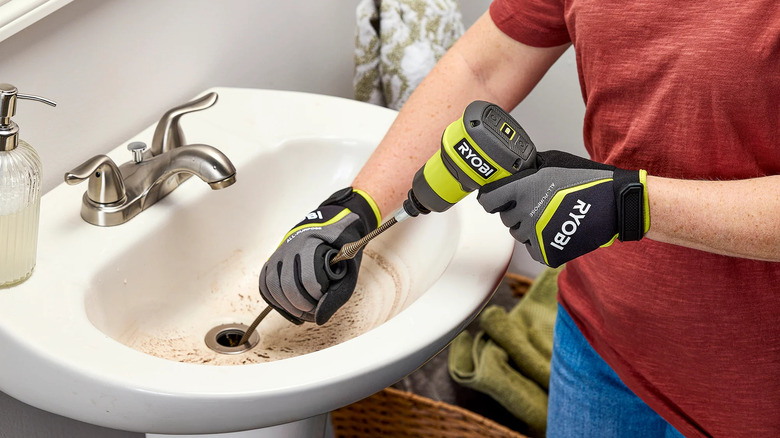 Person uses Ryobi USB Lithium Drain Auger to unblock a sink.