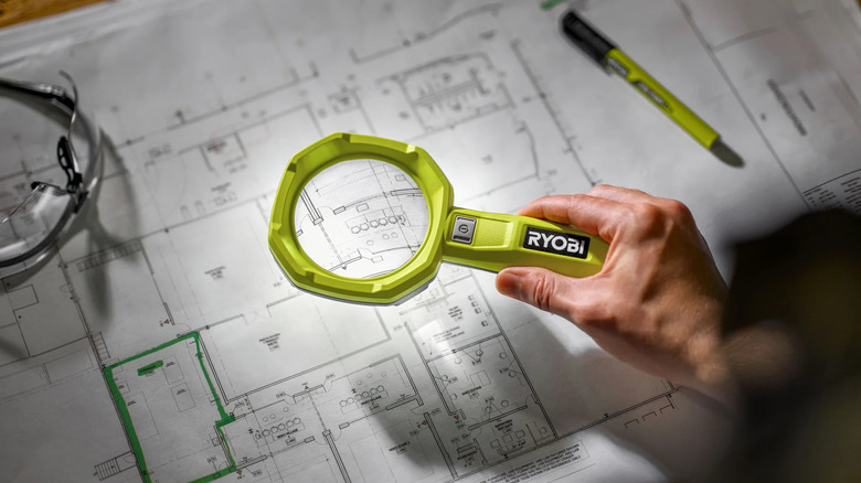 A person uses the USB Lithium LED magnifying light to inspect construction plans.