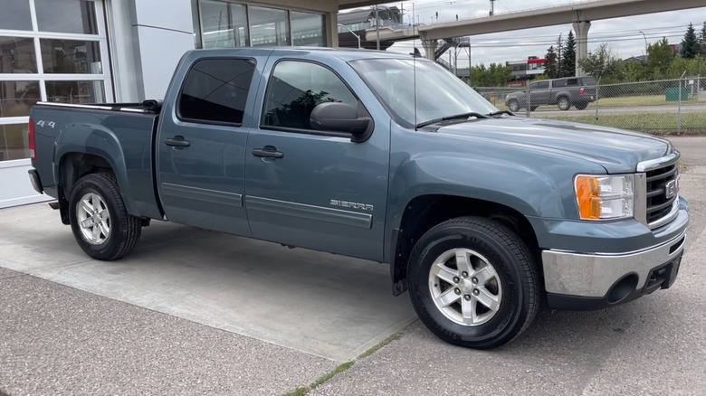 Blue-gray 2011 GMC Sierra 1500 parked in front of a building