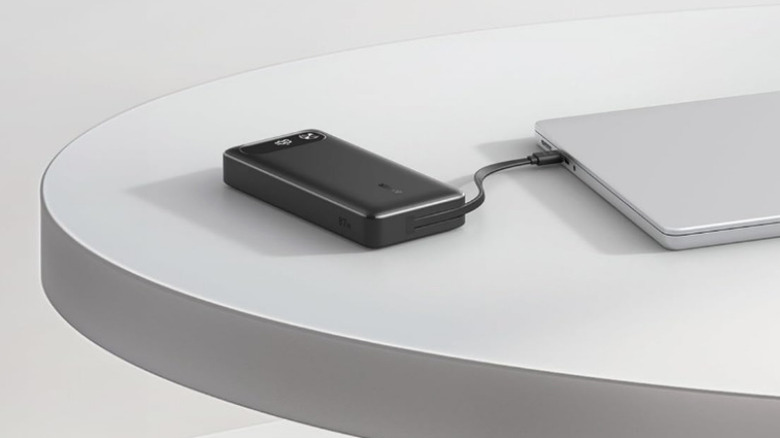 An Anker Power Bank on the desk plugged into a laptop.