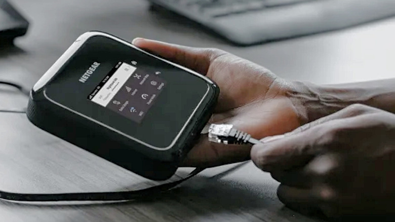 A man connecting an ethernet cable to the NETGEAR Nighthawk M6 Pro.