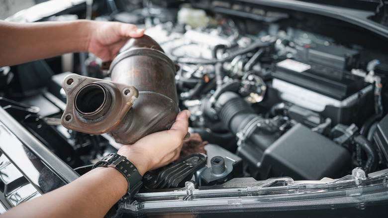 A person holding a catalytic converter in both hands