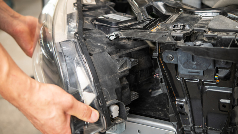 A person installing a headlight assembly onto a car frame