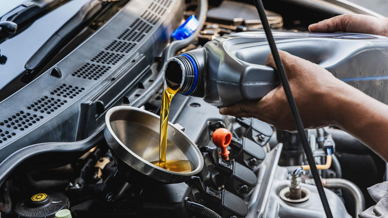 Mechanic pours engine oil into engine