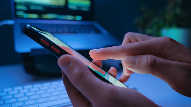 A hand tapping on the screen of a phone.