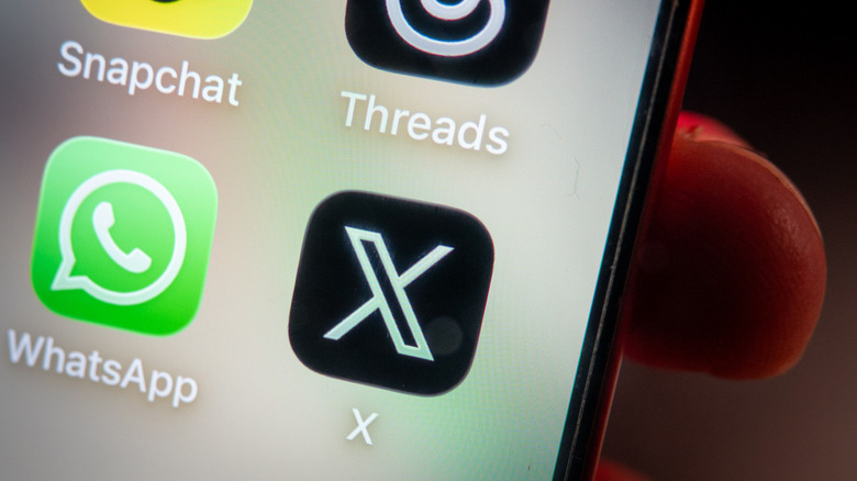 Snapchat, Threads, X, and WhatsApp icons on a phone.
