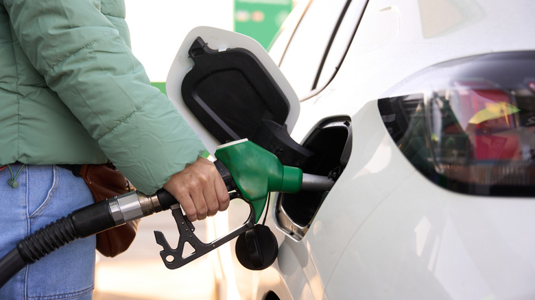 A woman refuels a car