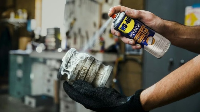A person spraying WD-40 Specialist Corrosion Inhibitor on a piece of metal