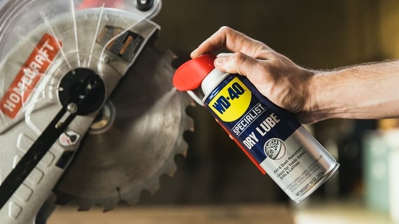 A person spraying a WD-40 Specialist Dry Lube on a saw