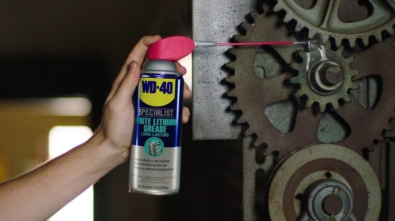 A person using WD-40 Specialist White Lithium Grease on a mechanical gear