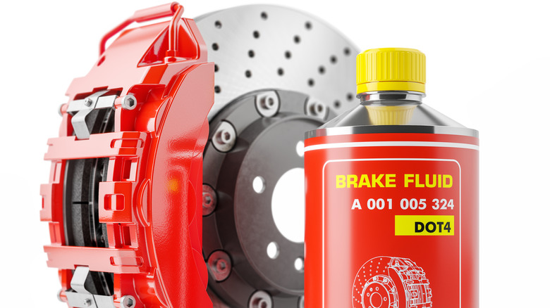 A brake rotor with red brake calipers and a can of red brake fluid beside it