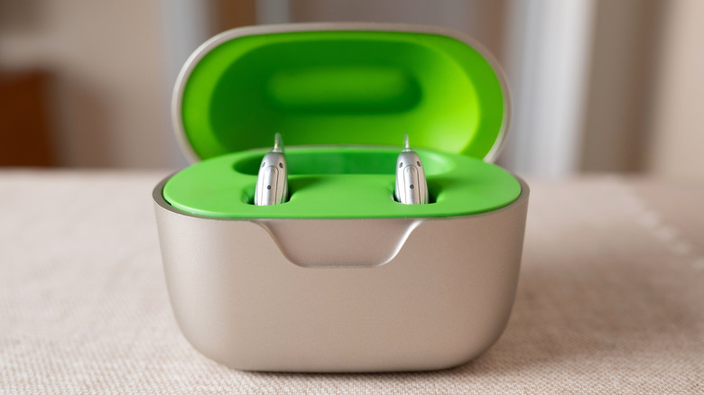 Hearing aids in a green and chrome rechargeable case.