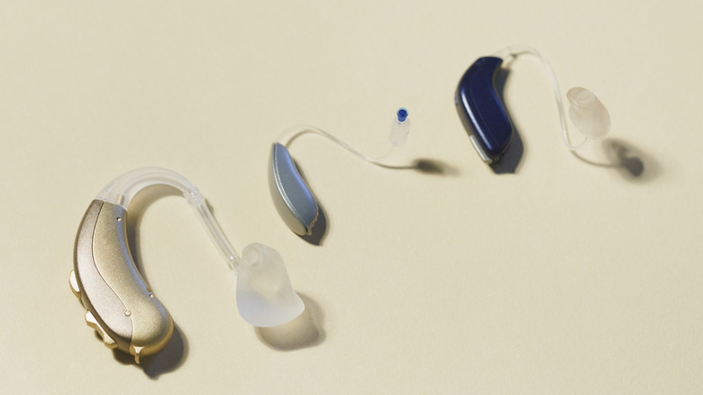 Three single hearing aids, all over-the-ear (OTE), in various sizes and colorrs with visible domes and pipes.