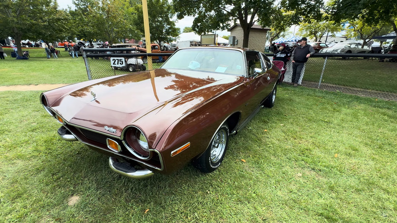 A reddish-brown AMC Matador from 1977 finished here in the coupe body style standing on grass in shade.