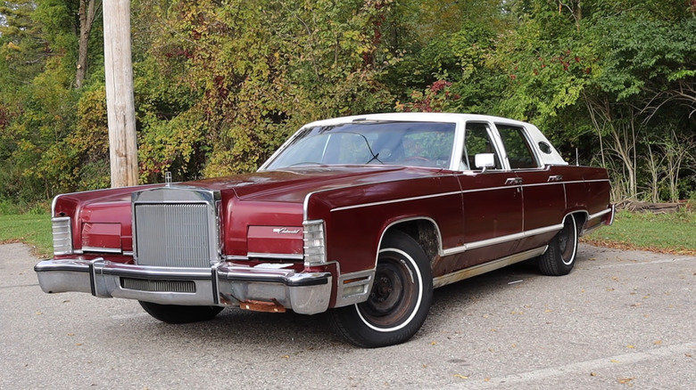 A 1978 Lincoln Continental Town Car with a white roof parked on a thin paved driveway.