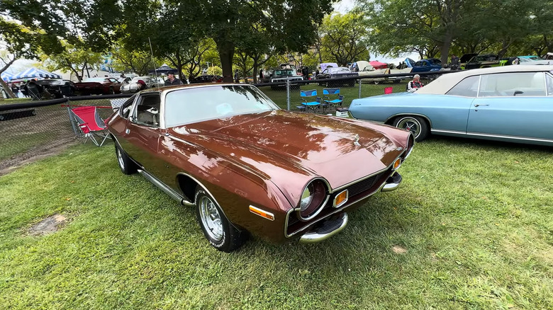 A burgundy metallic AMC Matador Barcelona coupe muscle car standing on grass at an outdoor show.
