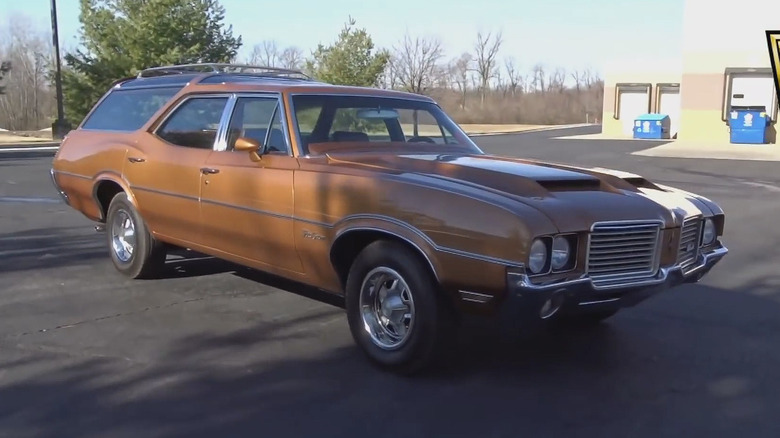 A 1970s Oldsmobile Vista Cruiser wagon pictured here parked on pavement in the afternoon sun in a vacant lot.