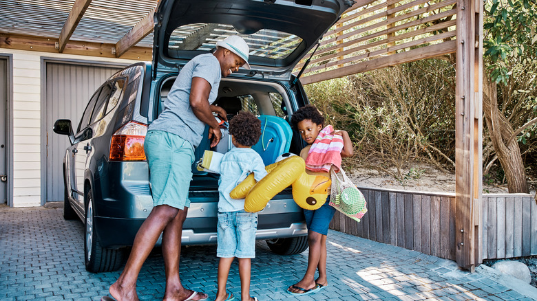 Family packing a car's trunk with various pool items