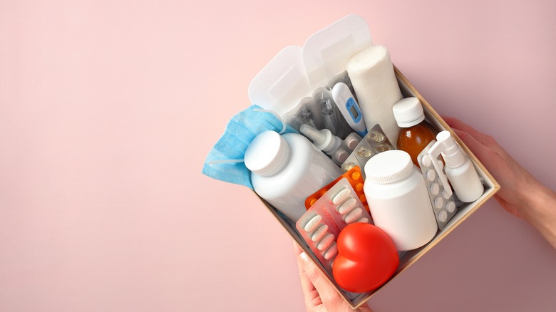 Hands holding a basket containing medicine and first aid items