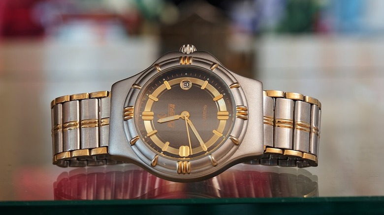An expensive-looking wristwatch resting on a reflective table