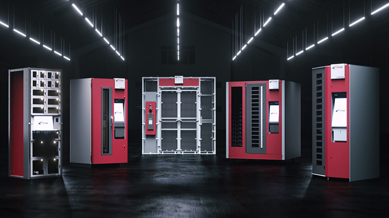 Five industrial vending machines placed in a darkly lit room.
