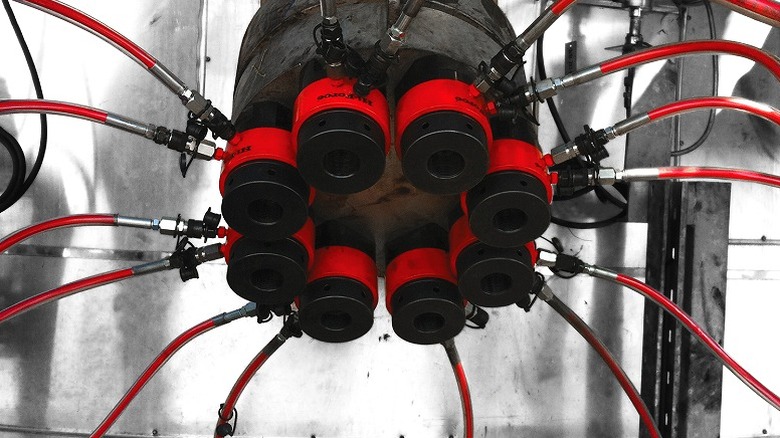 A red and black hydraulic cylinder connected to several pipes.