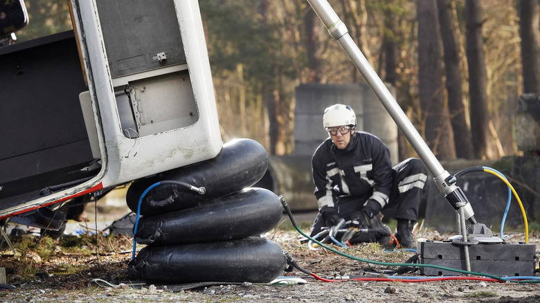 A worker using a Power Hawk lifting bag to lift a vehicle.