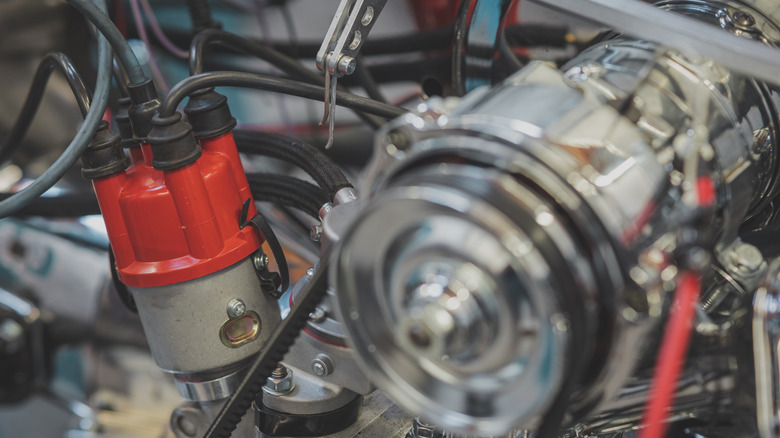 Distributor and distributor cap of a vintage car, visible ignition cables of a four cylinder engine of older type