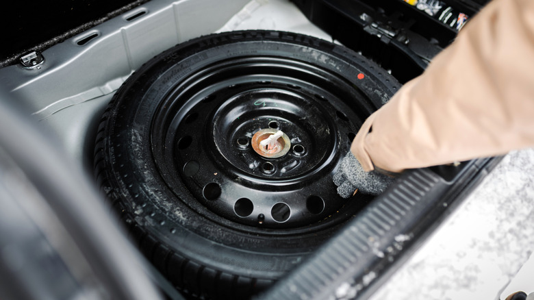 Driver taking out a spare tire from a trunk