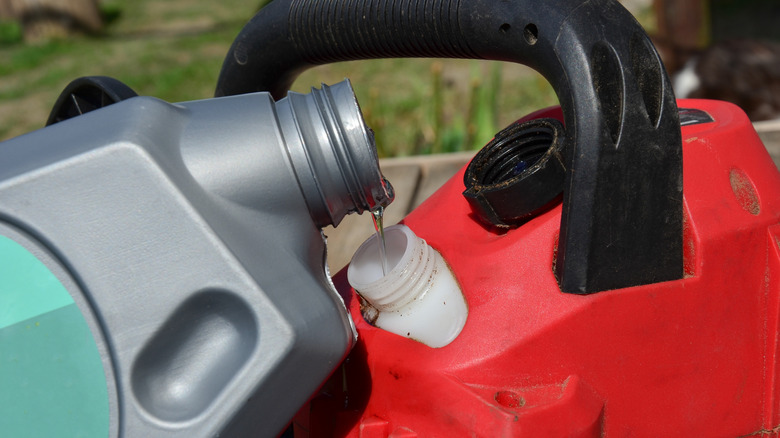 Oil being poured into a chainsaw's engine