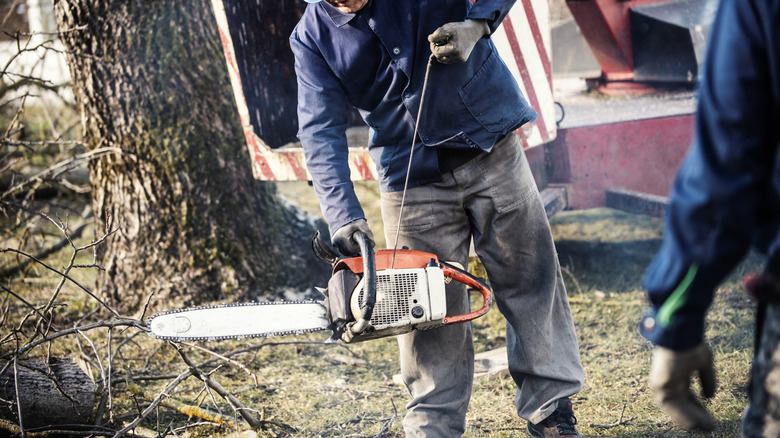 A person pulling the starter rope of a gas chainsaw