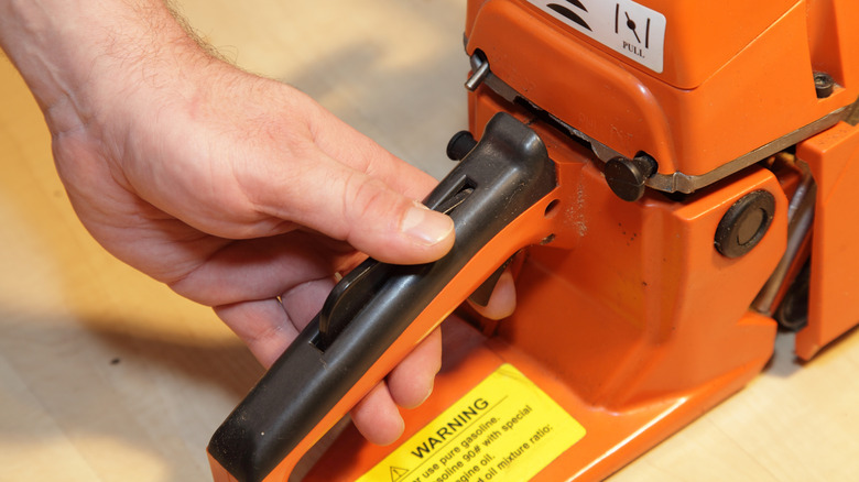 A person holding down a chainsaw's throttle