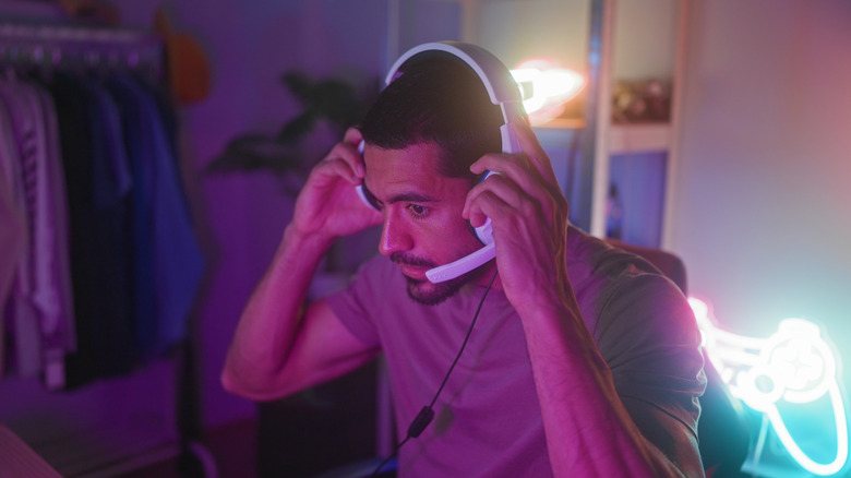 A person sitting at a computer desk wearing a wired headset in a residential bedroom