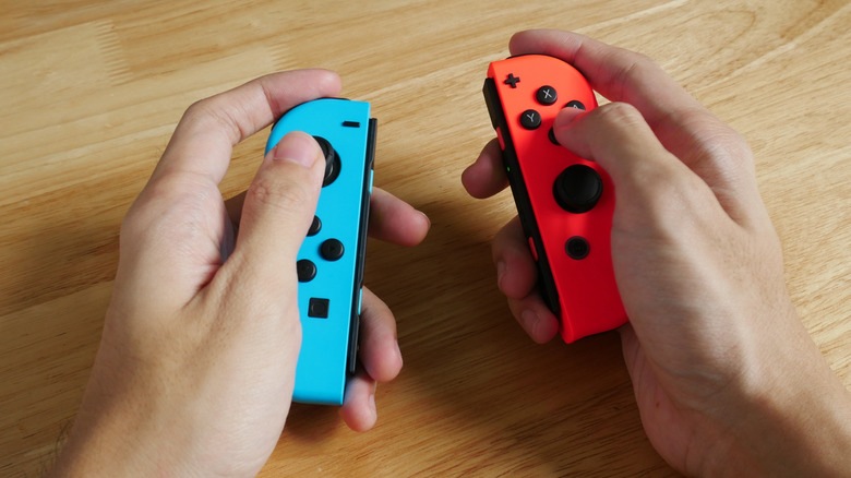 A pair of hands holding two Nintendo Switch Joy-Cons