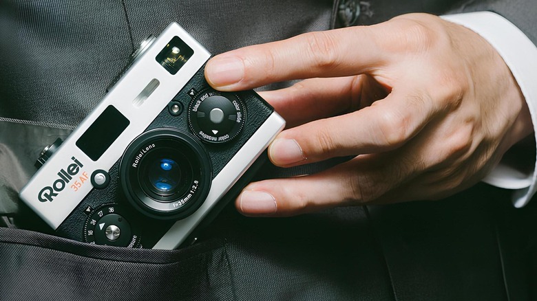 Man putting film camera in coat pocket