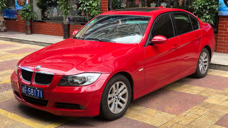 A red BMW 3-Series parked in front of a shop