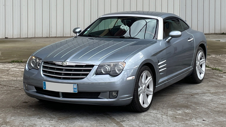 A gray Chrysler Crossfire parked by a large white building
