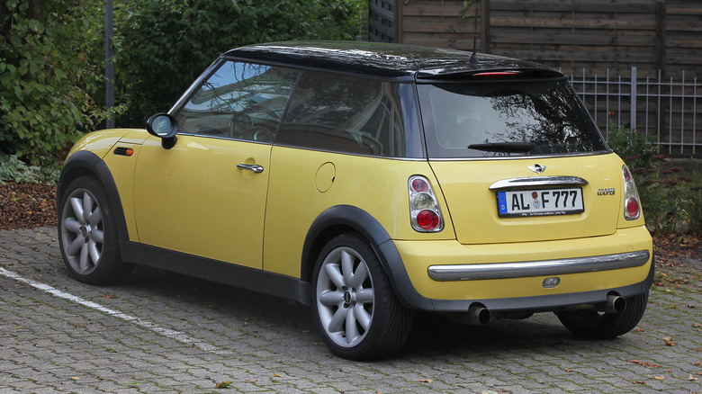 A yellow Mini Cooper in a parking spot