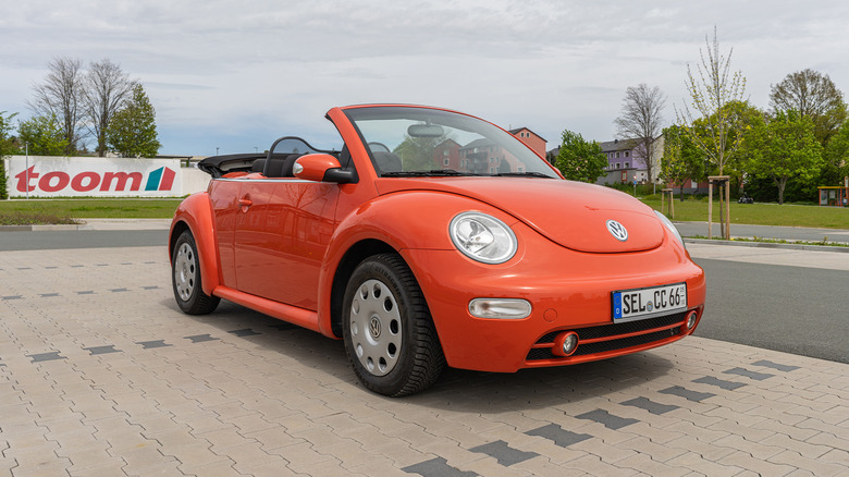 An orange Volkswagen Beetle convertible in a stylish parking lot