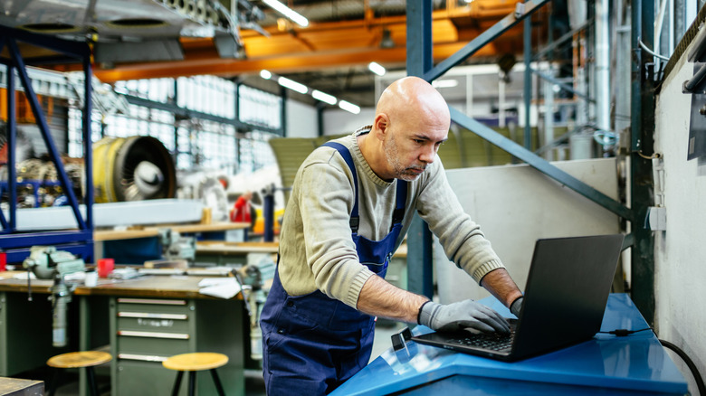 mechanic working in shop and using laptop