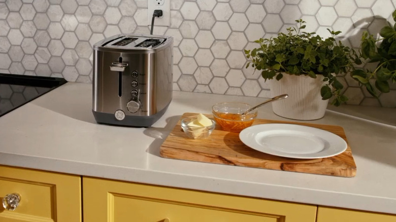 The GE 2-slice toaster on a kitchen counter next to a breakfast plate