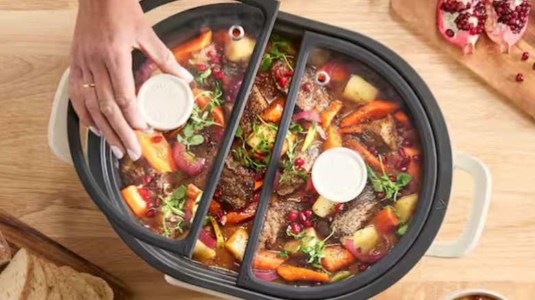 The 8-quart slow cooker with a full meal being cooked while the top is put on